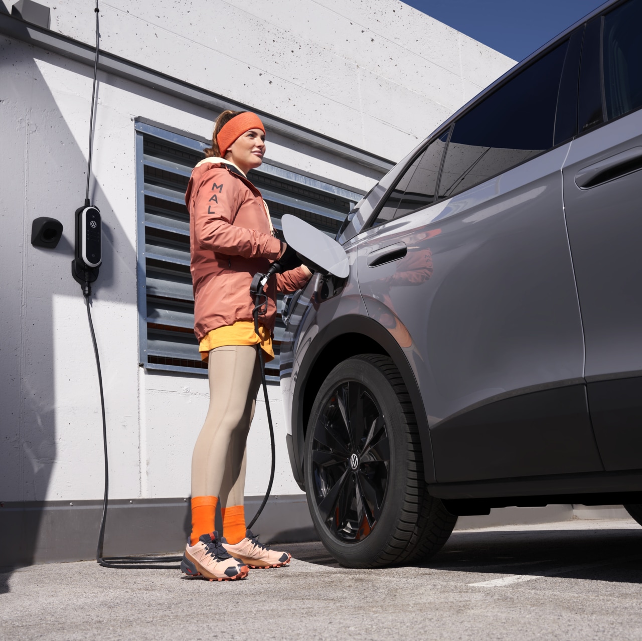 Frau lädt ihr E Auto an einer öffentliche Ladestation auf