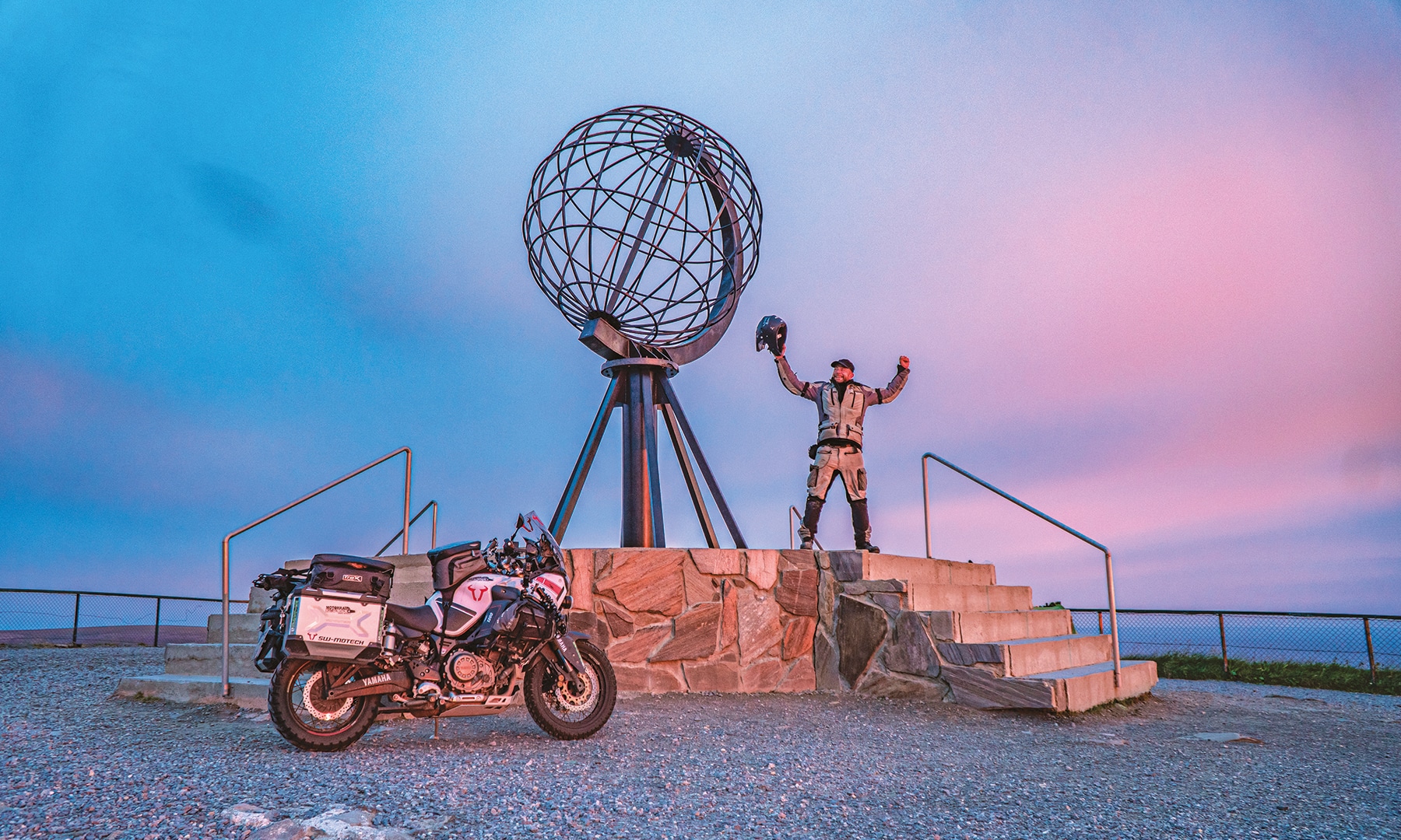erik peters mit seinen motorrad am nordkap vor einem metallglobus